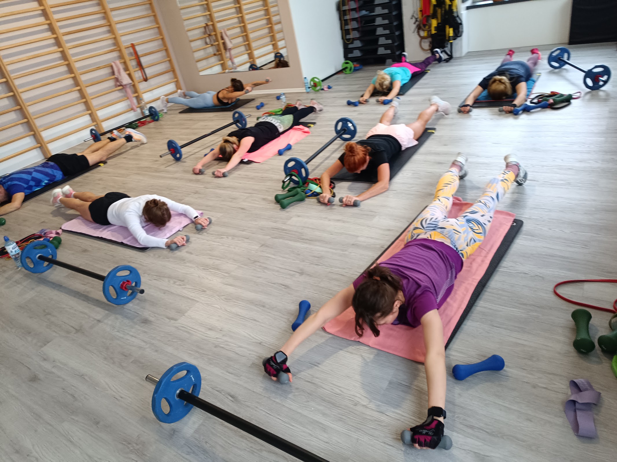 Grupowe zajęcia fitness w Body Center, klienci ćwiczący na matach z gryfami